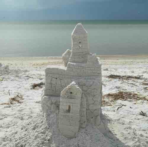 An ornate sandcastle on a white beach